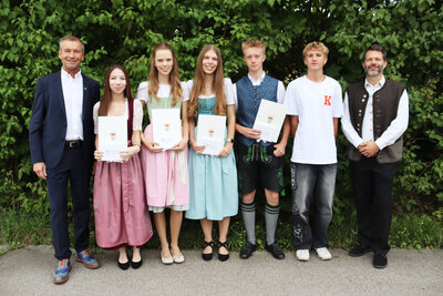 Bild vergr&ouml;&szlig;ern: Landrat Jens Zangenfeind (l.) und Direktor Tobias Schreiner (r.) gratulieren Luisa Lechner, Anna Faltermeier, Felizia Wagner, Florian Dotzauer und Bastian G&ouml;rner (v.l.) von der Realschule Gmund.